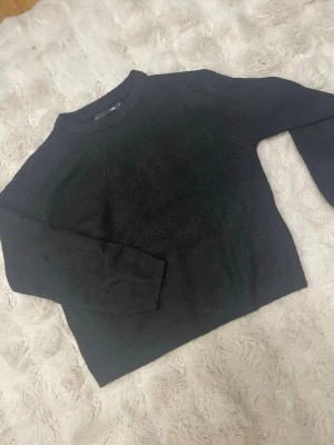 Svart stickad tröja från 157 XS - En svart stickad tröja från 157 i storlek XS. Tröjan har rund halsringning, ribbade muddar vid ärmslut och nederkant samt långärmade.