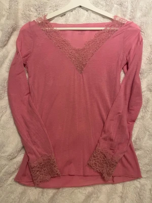 Rosa långärmad tröja från Intimissimi - Säljer en rosa långärmad blus från Intimissimi i storlek S. Toppen har v-ringad spets vid halsen och spetsdetaljer vid ärmsluten. Inga defekter, bara att skriva för fler frågor.