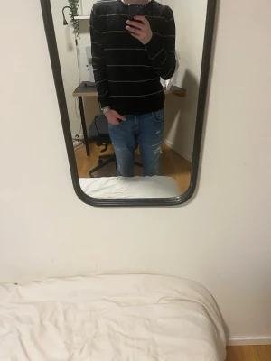 Svart randig tröja med vita linjer - Säljer en svart långärmad tröja med tunna vita ränder. Tröjan har en klassisk passform och är perfekt för dig som gillar en enkel men stilren look. Materialet känns mjukt och bekvämt, perfekt till jeans eller chinos.