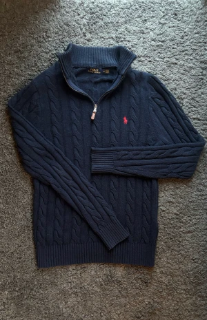 Ralph Lauren Zip Up  - Mörkblå stickad zip up tröja från Polo Ralph Lauren. Tröjan har kabelstickat mönster och halv dragkedja. Perfekt nu när det blir kyliga dagar.   📏Storlek: M 📐Passform: Normal passform  ✅Skick: 8/10 🧵 20% ull, 70% bomull, 10% nylon  🎨 Färg: Marinblå   Nypris drygt 2000kr, grym tröja! Priset är ej hugget i sten! ‼️Skickas samma dag eller dagen efter köpet genomförs‼️ 