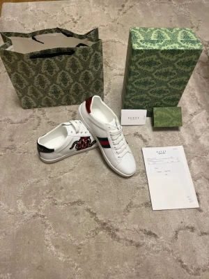 Vita ormdesign skor - Säljer ett par mycket fina skor som är helt nya endast prövade på. Allt på bilden medföljer och storleken är 44. 