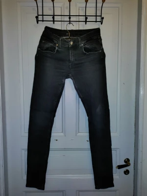 Svarta jeans/Tiger of Sweden - Svarta jeans från Tiger of Sweden, tillverkade i Italien. Modellen är slim fit med klassisk femficksdesign och smal passform hela vägen ner. Jeansen har midwaist och är gjorda i ett stretchigt jeansmaterial som sitter snyggt och bekvämt. Perfekt för dig som gillar stilrena och grischiga jeans