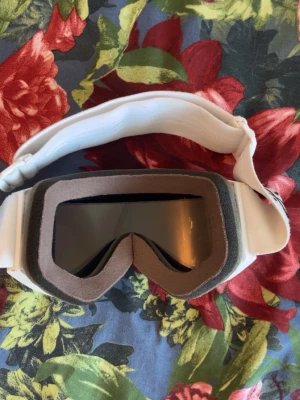 Vit skidväst från Dope - Säljer en vit skidväst från Dope med bred resår och svart logga på bandet. Västen har en stilren design med mjuk skumvaddering runt kanterna och slät yta. Perfekt för dig som vill ha en clean look i backen.