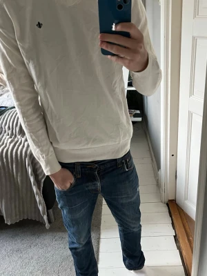 Vit v-ringad tröja från Morris - Vit v-ringad tröja från Morris med diskret broderad logga på bröstet. Tröjan är långärmad och har ribbade muddar vid ärmslut och nederkant. Tillverkad i mjuk bomull, perfekt för dig som gillar stilrena och klassiska plagg. Hör av dig vid funderingar 🤗