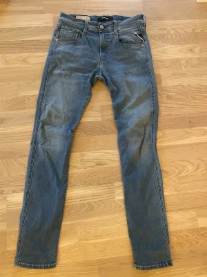 Replay Hyperflex Anbass jeans ljusblå - Snygga Replay Hyperflex Anbass jeans i klassisk ljusblå tvätt med fem fickor och smal passform. Jeansen har stretchigt material för extra komfort och detaljer som Replay-logga på bakfickan och läderpatch i midjan. Perfekt för dig som gillar stilrena och bekväma jeans. Skick 9/10. Använda 3-5 gånger. Kontakta mig för fler bilder.