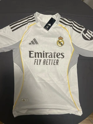 Real Madrid tröja  - Real Madrid matchtröja med Mbappé och nummer 10 på ryggen.  gula inslag längs sidorna. Perfekt för fotbollsfans som vill ha en snygg och modern look.