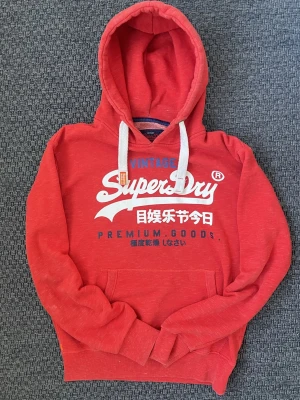 2000s vintage SuperDry Hoodie (sällsynt) - Säljer nu denna riktigt snygga vintage 2000s hoodie från Superdry i näst intill nyskick!😊 Säljs ej längre nu och är därav eftertraktad🙌 Riktigt varm och skön så passar perfekt nu till vintern ❄️Storlek L. Skriv vid funderingar📲🤝