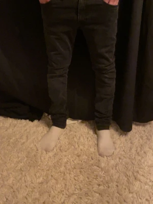 Svarta skinny jeans - Säljer ett par svarta skinny jeans med smal passform och klassisk femficksdesign. Jeansen har en enkel look och är perfekta för dig som gillar en tajt stil. Materialet är jeans och färgen är helt svart.