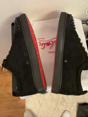 louboutin  - Säljer ett svarta skor  och klassisk röd sula. Skorna är i läder och har snörning. Perfekta för dig som vill sticka ut med en edgy och lyxig stil.
