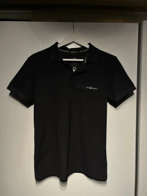 Svart pikétröja SAIL RACING - Helt ny sail racing pike. Den är i storlek S, pch passar våran modell perfekt som är 179. Ny pris är ungefär 800kr. 🤩