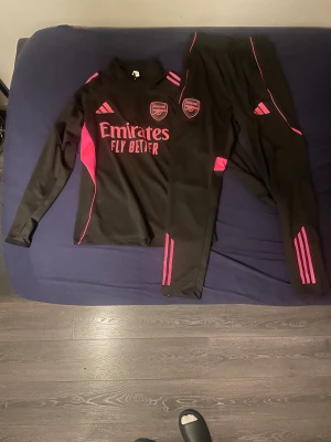 Arsenal Tracksuit Adidas - Arsenal tracksuit Rosa/svart. Helt ny säljer den för att jag tog fel storlek. Jätte bra för träningar och andra aktiviteter, bra material och jätte bra pris. Köpte för 1200kr storlek M. Pris kan diskuteras 