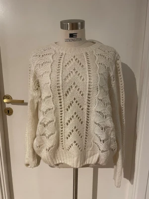 Vit stickad tröja från L.O.G.G - Säljer en vit stickad tröja från L.O.G.G med snyggt hålmönster och ribbade muddar. Tröjan har rund hals och långärmade ärmar, perfekt för dig som gillar en mysig och stilren look. Passformen är normal och materialet känns mjukt och värmande.