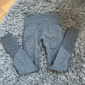 Grå sömlösa leggings i S - Grå sömlösa leggings med hög midja och snygga meshdetaljer på benen. Tillverkade i stretchigt material (92% polyamid, 8% elastan) som sitter tight och bekvämt. Perfekta för gymmet eller chill hemma.