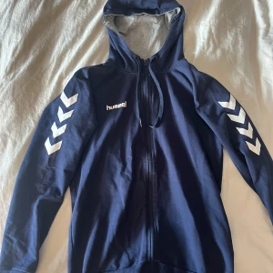 Marinblå Hummel hoodie med dragkedja - Säljer en blå hoodie från Hummel som har full dragkedja. Den är lite uttvättad men fortfarande i bra kvalité! 