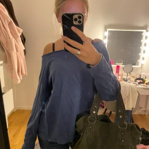 Blå offshoulder tröja i bomull - Säljer en blå offshoulder tröja med lång ärm och loose passform. Tröjan är i mjuk bomull och har en avslappnad vibe med bred halsringning som sitter snyggt över ena axeln. Perfekt till jeans för en chill look.