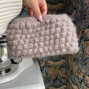 Beige stickad kuvertväska - Supermysig beige clutch/necessär i virkat material med bubblig struktur. Perfekt att bära i handen och är rymligare än vad man skulle kunna tro. Längd 24cm, höjd 13cm, bredd 3cm. Skriv gärna till mig om du har frågor eller ett prisförslag💕