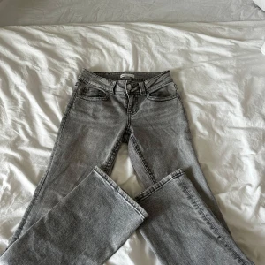 Gråa bootcut jeans från Gina tricot, stl 36 - Säljer ett par grå jeans från Gina Tricot i storlek 36. De har klassisk femficksdesign, Bootcut och snygga detaljer med knappar på bakfickorna. Jeansen har en cool tvättad look och är tillverkade i jeansmaterial med dragkedja och knapp framtill. Används 1 gång då dom är för små.