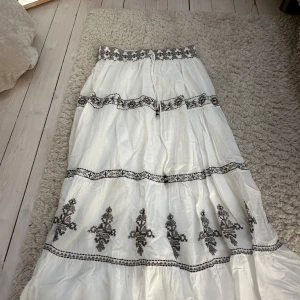 Zara långkjol - Jättefin långkjol från Zara. Köpt för ca ett år sedan men är i väldigt fint skick. Det är en vit kjol med svarta broderade detaljer
