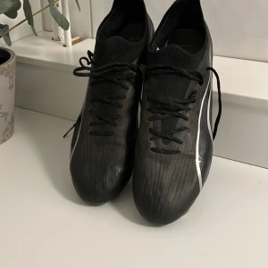 Puma Ultra FG/AG - Hej, säljer nu detta par fotbollsskor i mycket bra skick där det endast är dobbarna som är lite slitna. Skorna funkar lika bra på gräs som på konstgräs(FG/AG). Puma passar dig som vill ha otroligt sköna skor där du också flyger fram på planen då skorna är mycket lätta. Vid frågor är det bara att höra av sig. Nypris 2499| Mitt pris 799.