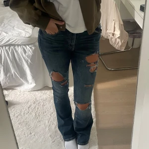Slitna bootcut jeans - Säljer ett par blå utsvängda jeans med slitningar från Zara i storlek 34. Hör av er vid frågor😊