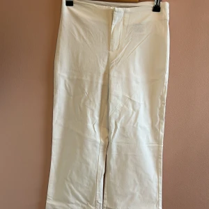 Vita raka byxor från Divided XS - Snygga vita byxor från Divided i storlek XS. Byxorna har rak passform och klassisk midja, perfekta till en clean och fräsch look. Tillverkade i ett mjukt bomullsmaterial som känns skönt mot huden. Stängs med knapp och dragkedja framtill.