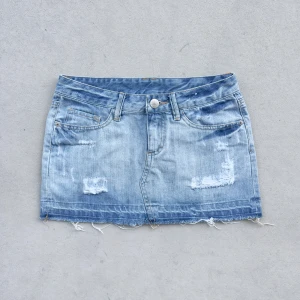Lågmidjad jeanskjol med revor  - 2000s low waist ljusblå jeanskjol med snygga slitningar i jättebra skick, mått på sista bilderna 