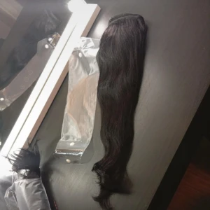 Svart löshårstofs - Långt, vågigt svart löshår med clip-on-fäste. Perfekt för att snabbt få längre och fylligare hår. Håret har en naturlig glans och är lätt att styla. Kommer i en praktisk förpackning för enkel förvaring. Ca 45 cm från Rapunzel 100 gram knappt använd.