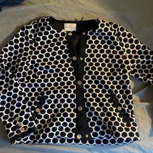 Prickig kofta  - Snygg mörkblå vit overshirt från Holly & White med stora prickar och markerade svarta detaljer längs knäppningen och fickorna. Jackan har knappar framtill och på ärmsluten, samt två fickor. Aldrig använd och har prislapp kvar 