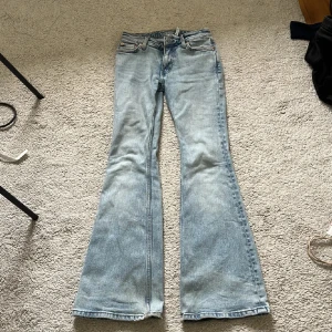 Bootcut jeans från Weekday ljusblå - Säljer ett par ljusblå bootcut jeans från Weekday i klassisk denim. Modellen har utsvängda ben och normal passform. Dom är lite slitna som ni ser på bild tre. Storlek w24 passat mig som är c 160