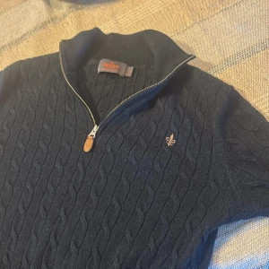 Mörkblå kabelstickad tröja med halv dragkedja - Säljer en mörkblå kabelstickad halfzip tröja från Morris i storlek S men sitter som storlek xs. Jag är 174 och tycker att den sitter en aning för tight på mig.