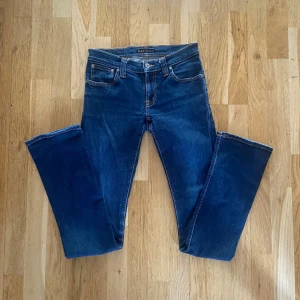 Blå jeans från Nudie Jeans W27 L34 - Snygga blå jeans från Nudie Jeans med klassisk femficksdesign och kontrastsömmar. Modellen har raka ben och normal passform. Bakfickorna har Nudie Jeans ikoniska broderi. Perfekta till sneakers eller boots. Använda ett fåtal gånger skick 8,5/10 Ny pris~1300kr Mitt pris 400🤩