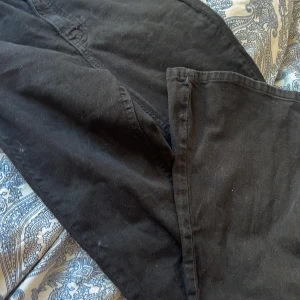 Svarta jeansbyxor från Gina Tricot - Svarta jeansbyxor från Gina Tricot med klassisk femficksdesign och bälteshällor. Byxorna har raka ben och är tillverkade i ett mjukt bomullstyg med lite stretch. Perfekta till sneakers eller boots och enkla att matcha med olika stilar.