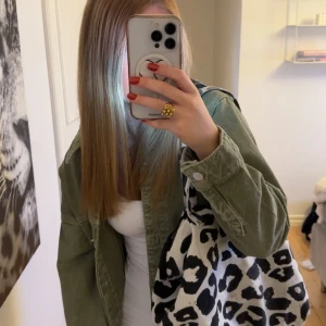 Leopardmönstrad tygväska  - Säljer en stor och rymlig shoppingväska i vitt tyg med svart leopardmönster. Väskan har två handtag och en cool patch framtill. Perfekt för att bära allt du behöver till skolan eller stan.