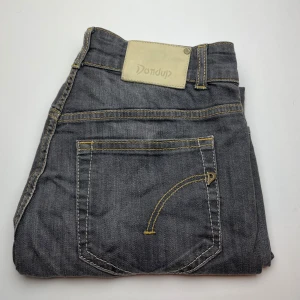 Dondup jeans  - Snygga grå jeans från Dondup med klassisk femficksdesign och kontrastsömmar i gult. Jeansen har en rak passform och är tillverkade i mjukt bomullstyg. Perfekta för dig som gillar en stilren look med lite edge.