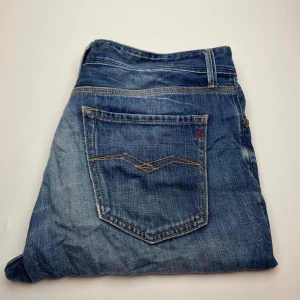 Blå Replay Leena jeans med slitningar - Snygga blå jeans från Replay, modellen Leena. De har coola slitningar och en tvättad look med ljusare partier. Klassisk femficksdesign och kontrastsömmar på bakfickan. Perfekta för dig som gillar en avslappnad och trendig stil.