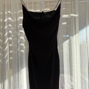 Svart glittrig klänning från H&M - Säljer en svart glittrig klänning från H&M i storlek 44. Klänningen har tunna axelband, en snygg draperad halsringning och är figurnära. Materialet är glittrigt med små rosa detaljer som syns i närbild. Perfekt för dig som vill sticka ut med lite extra shimmer.