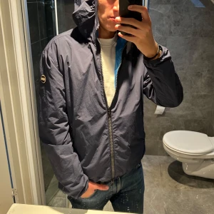 Mörkblå Colmar vindjacka  - Säljer en mörkblå Colmar vindjacka som är riktigt schysst nu till hösten. Jackan är i mycket bra skick och har inga defekter. Jag är 188cm och bär storlek 56 vilket jag anser är optimalt. Skriv vid frågor;)