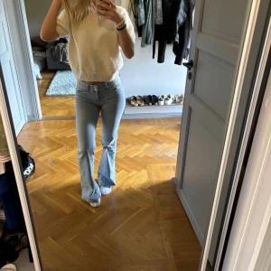 Bootcut ljusblå jeans med rosa broderi - Säljer ett par ljusblå bootcut jeans med snygg rosa broderad detalj på bakfickan. normal passform. Använda två gånger 
