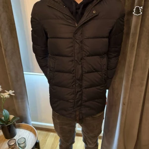 Svart pufferjacka från Herno - Säljer en svart pufferjacka från Herno med huva och diskret dragkedja framtill. Jackan har en stilren, quiltad design med två sidofickor och lång ärm. Materialet är syntet och jackan har en normal passform som sitter snyggt på kroppen. Finns liten defekt men inget som syns eller man tänker på när man bär den😊