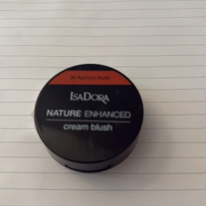 Isadora Nature Enhanced Cream Blush - Snygg krämrouge från Isadora i färgen 30 Apricot Nude. Kommer i en rund svart dosa med spegel och medföljande borste. Perfekt för att ge kinderna en fräsch aprikos-tonad glow. Smidig att ta med i väskan och enkel att applicera med den lilla borsten. Aldrig använd då den har plasten och allt kvar endast öppnad.. går att buda!!