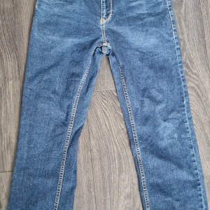 Levi's blå jeans straight leg - Byxorna har fem fickor, gul kontrastsöm och normal midja. Perfekt passform för dig som gillar en modern och stilren look. Levi's patch bak på linningen och ikonisk röd etikett vid bakfickan. De är i Junior storlek 14A