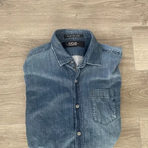Blå jeansskjorta från Replay - Snygg blå jeansskjorta från Replay med klassisk krage, bröstficka och knappar framtill. Riktigt snygg och inga defekter. Passar S