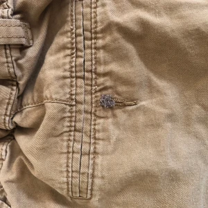 Beiga shorts från One 87 Six (H&M) - Säljer ett par beiga shorts från One 87 Six  (H&M) strl: 146. de har justerbar midja🥰 de är använda en sommar och säljs pga för små🤗 de är i okej skick men saknar en knapp bak💕‼️pris kan diskuteras‼️