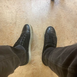 Svarta Lanvin sneakers, glansig toe cap - Säljer ett par svarta Lanvin. Skorna har rund tå, platt vit sula och klassisk snörning. Perfekt för dig som gillar stilrena och lyxiga sneakers med en cool vibe.. Glanset går att fixa med putsning. PRIS KAN DISKUTERAS!!!!