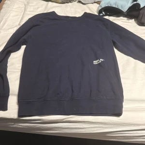 Mörkblå sweatshirt från Replay - Mörkblå sweatshirt från Replay med vit logga framtill och tryck på ryggen. Klassisk rund hals och långa ärmar. Tillverkad i mjuk bomull, perfekt för en chill och stilren look.