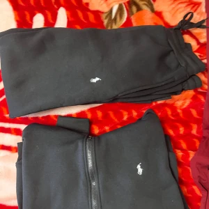 Svart hoodie från Polo Ralph Lauren - Svart hoodie från Polo Ralph Lauren med dragkedja framtill och klassisk huva.  har det ikoniska broderade logotypen på bröstet och är tillverkad i mjukt bomullsmaterial. Perfekt för en chill och stilren look.