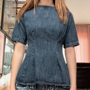 Mörkblå jeanstopp - Säljer en snygg mörkblå korsettinspirerad topp i jeansmaterial. Toppen har korta ärmar, markerad midja och rund halsringning. Aldrig använd, endast testad.