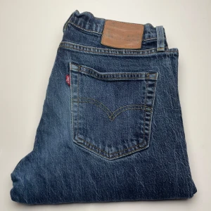 Levi's 511 blå jeans - Klassiska Levi's 511 jeans i blå denim med snyggt slitna detaljer. Modellen har en smal passform och ikonisk bakficka med gul söm samt läderpatch i midjan. Perfekta för dig som gillar en tidlös och clean look.