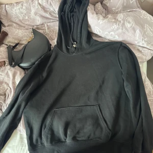 Svart hoodie från Divided, storlek S - Svart hoodie från Divided i storlek S. Klassisk modell med huva och känguruficka framtill. Mjuk och skön, perfekt för chill dagar. Långärmad och i bomullsmix som känns bekväm mot huden.