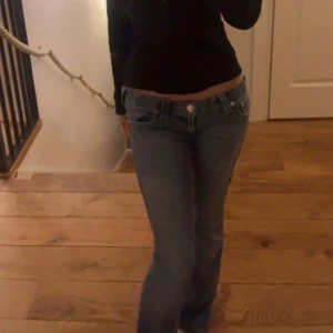 True religon jeans - Säljer ett par klassiska blå jeans med låg midja och bootcut-snitt. Jeansen har dragkedja och knapp framtill. Perfekta för dig som gillar en avslappnad och tidlös look. Materialet är jeans i bomull.